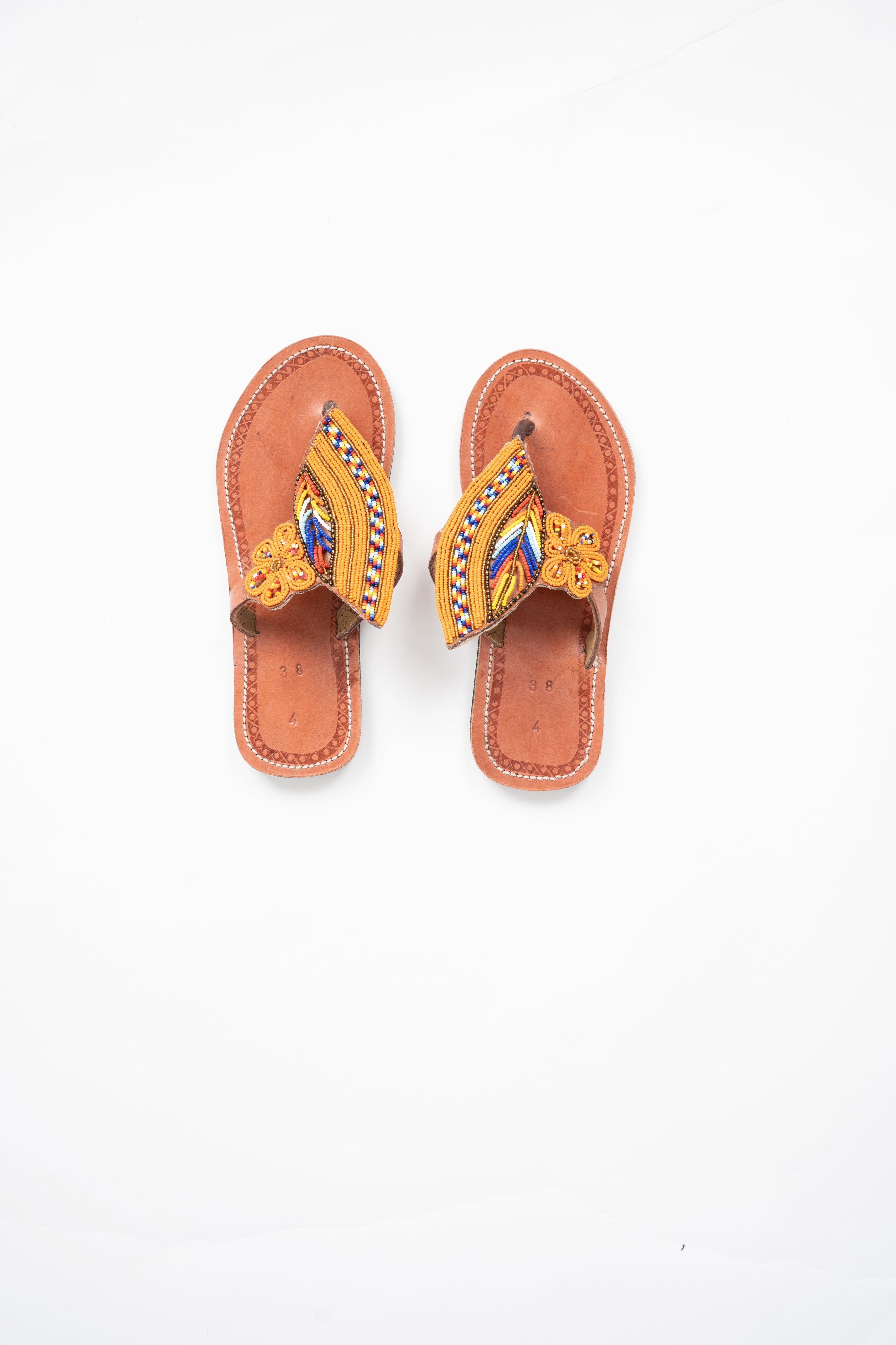 Pair of sandals with decorative straps on a white background