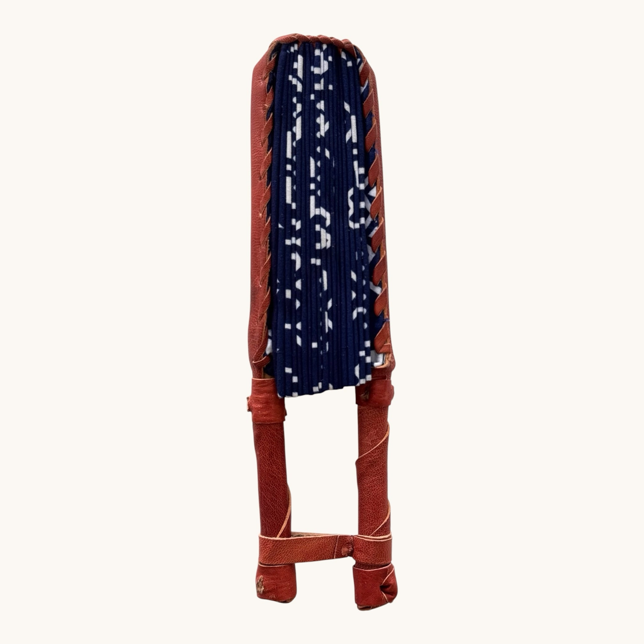 Hues by Kui folding hand fan in deep blue fabric with white geometric patterns and brown leather handle.