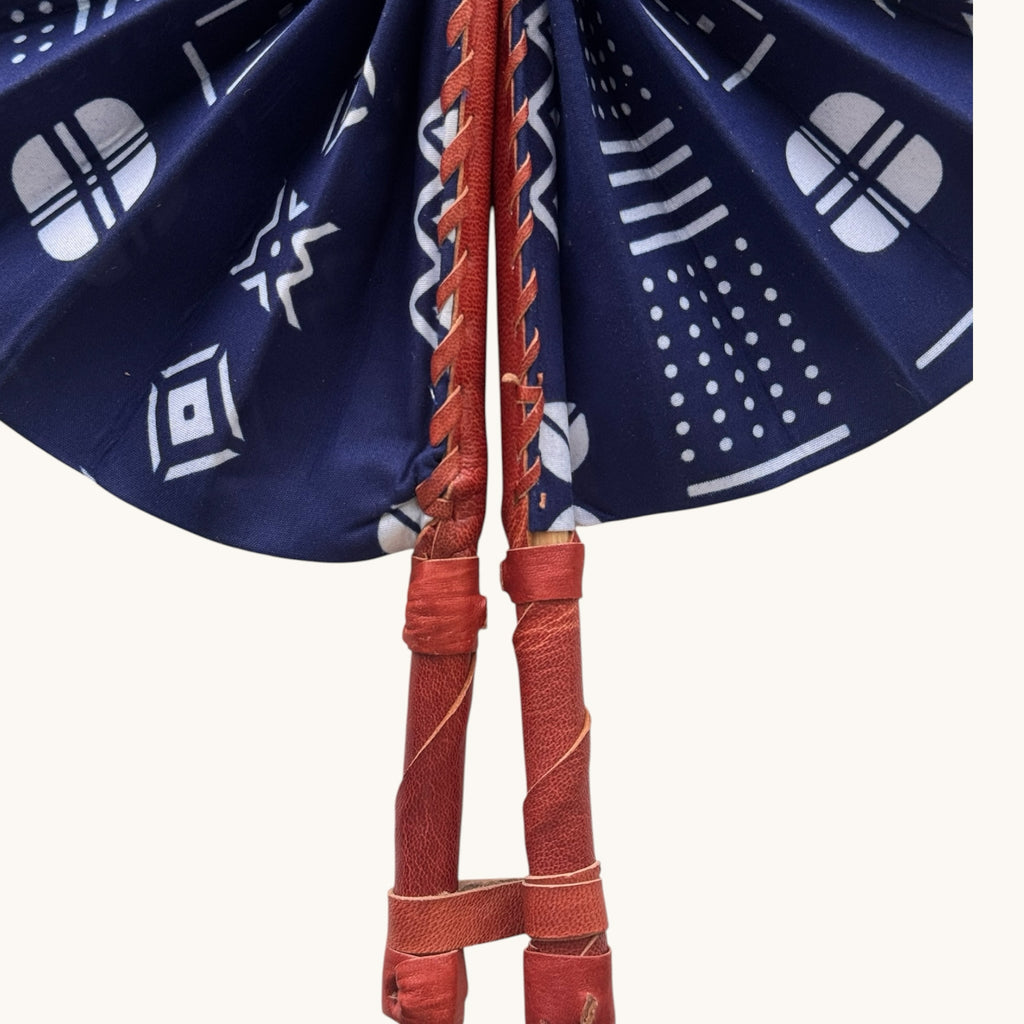 Hues by Kui handheld folding fan in deep blue fabric with white geometric mud cloth patterns and leather handle.