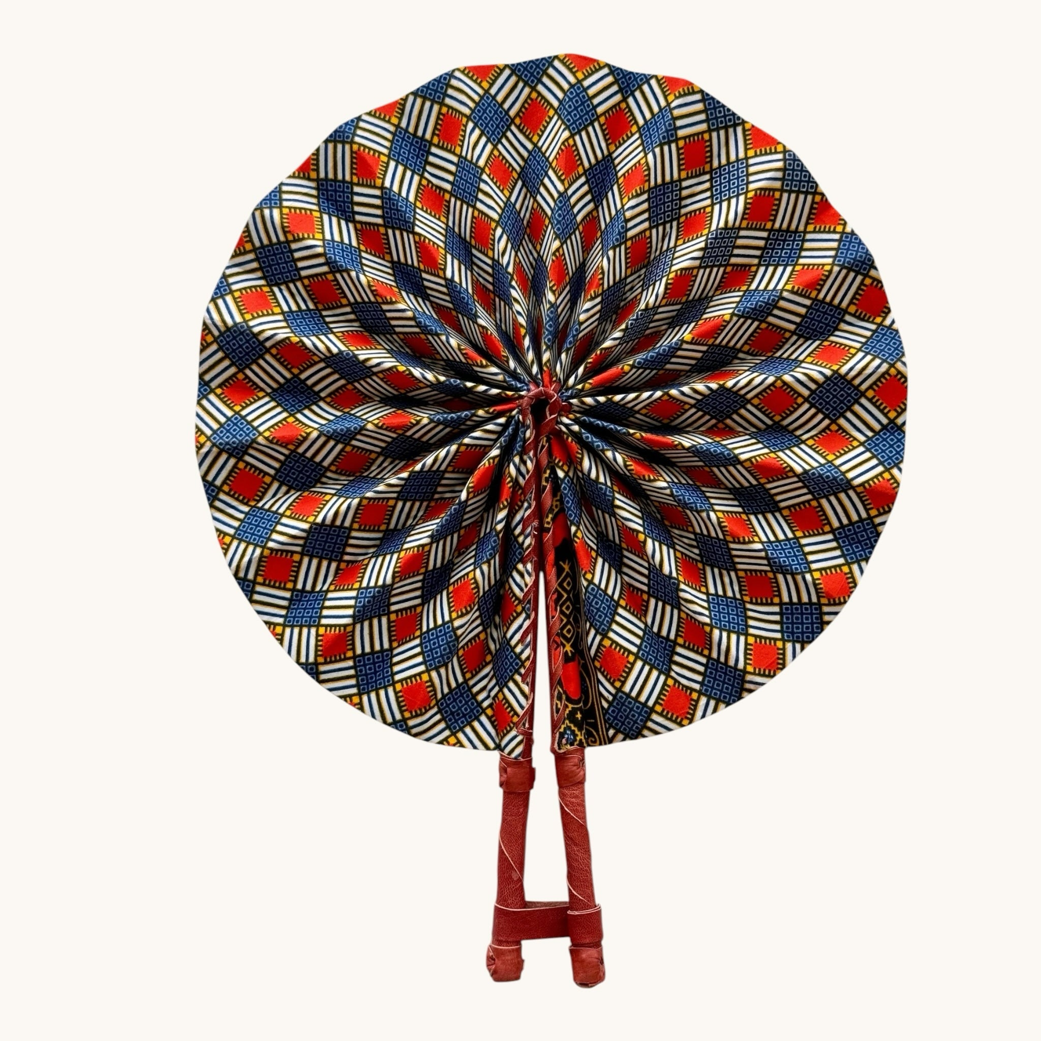 Hues by Kui traditional folding fan with vibrant red, blue, and white geometric Ankara print and leather handles.