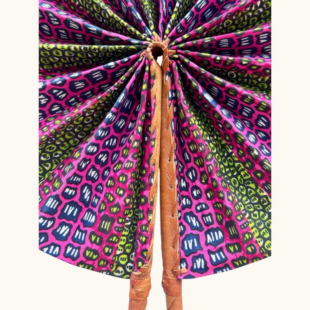 Hues by Kui handcrafted folding fan with vibrant pink, green, and blue geometric fabric and a leather-wrapped handle.