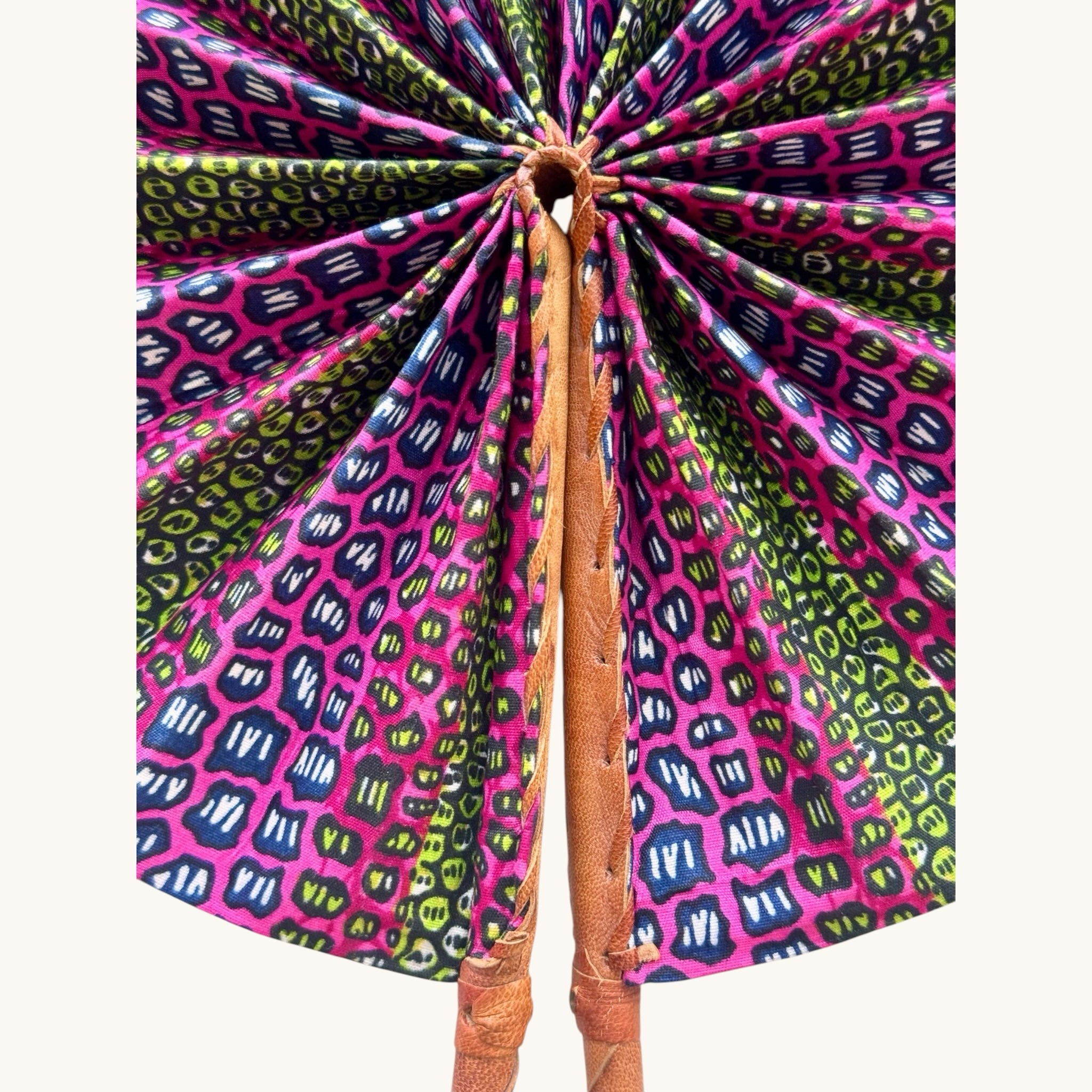 Hues by Kui handcrafted folding fan with vibrant pink, green, and blue geometric fabric and a leather-wrapped handle.