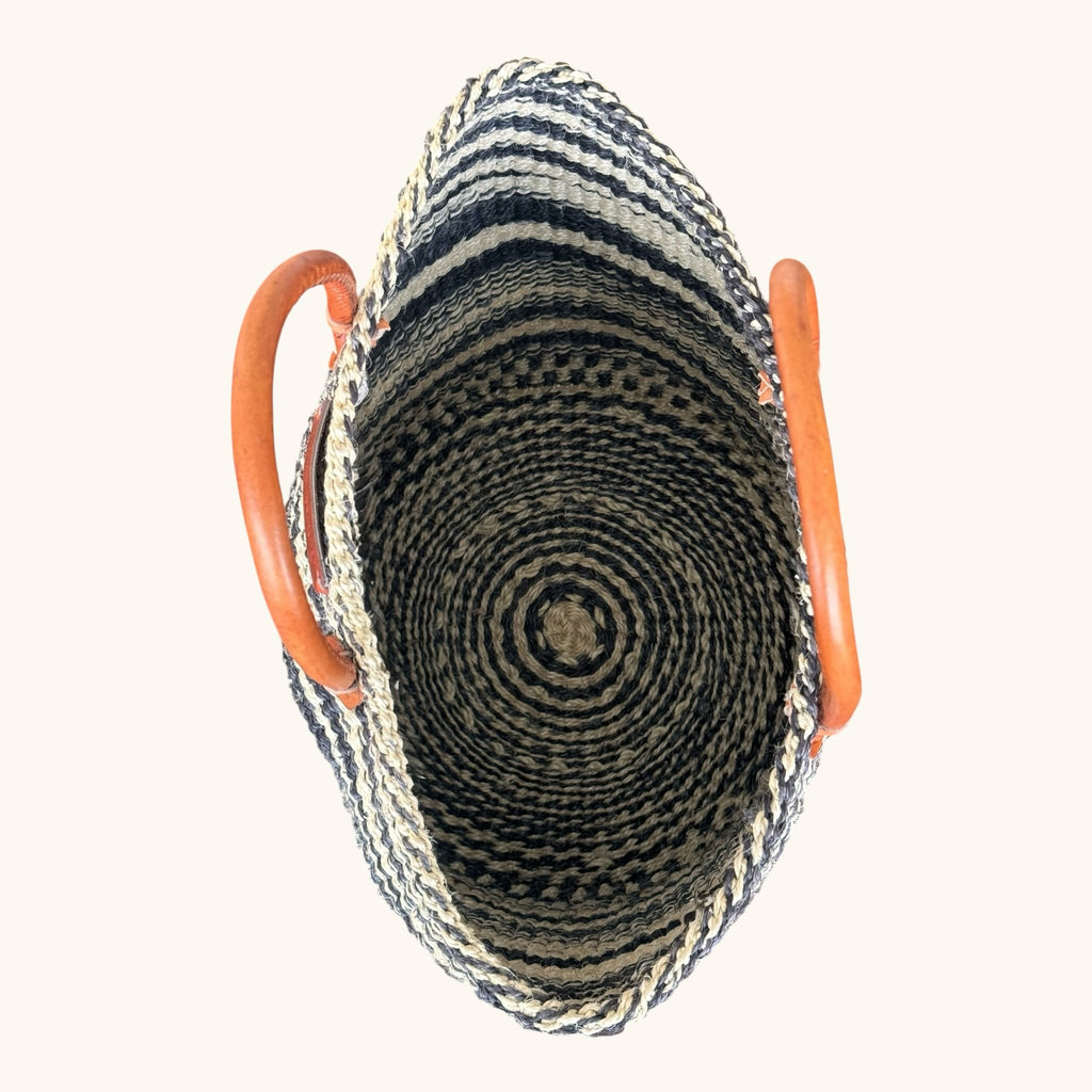 Hues by Kui handwoven straw tote bag with monochrome striped pattern and tan leather handles, top-down view.