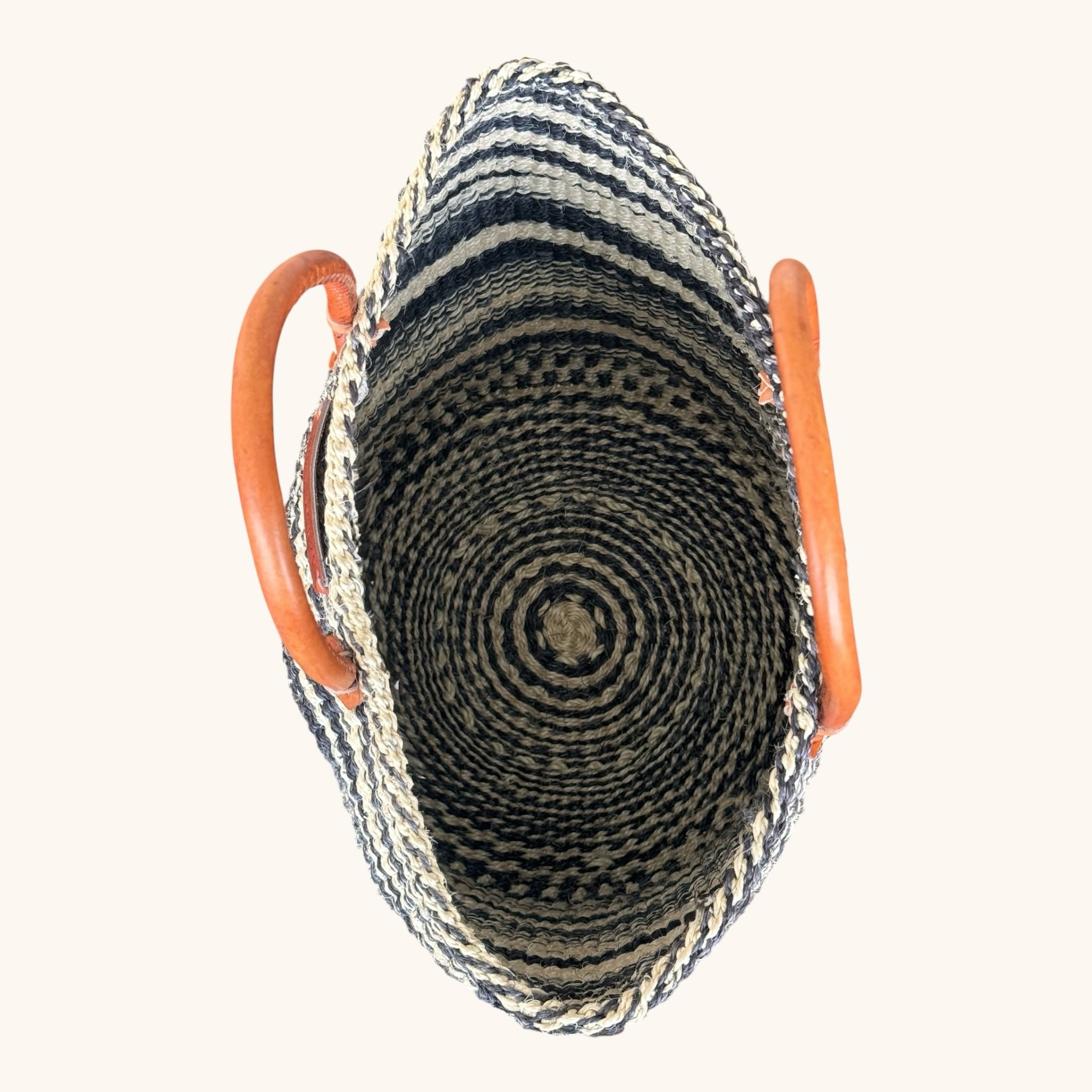 Hues by Kui handwoven straw tote bag with monochrome striped pattern and tan leather handles, top-down view.