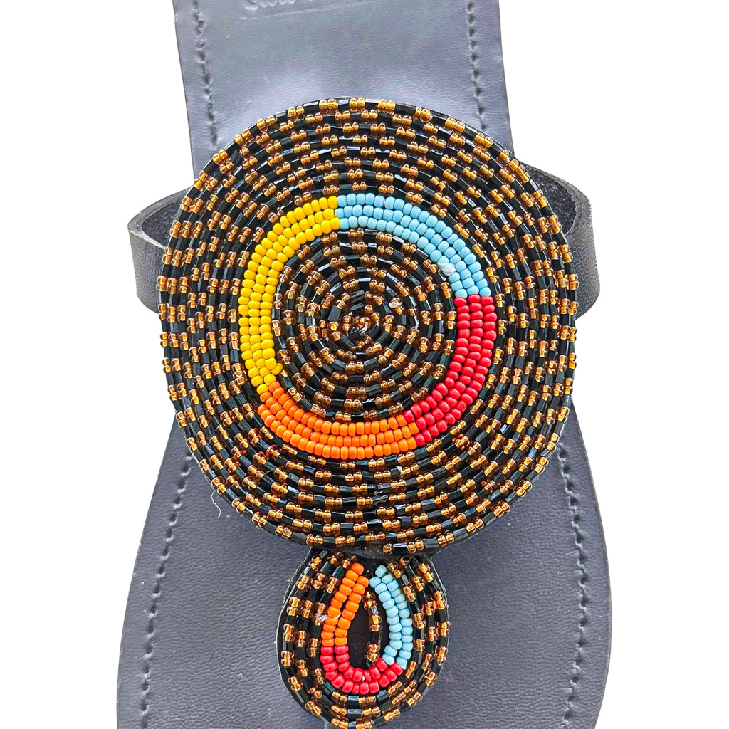 Close up of circular multicolor beadwork on Nuru black leather sandal
