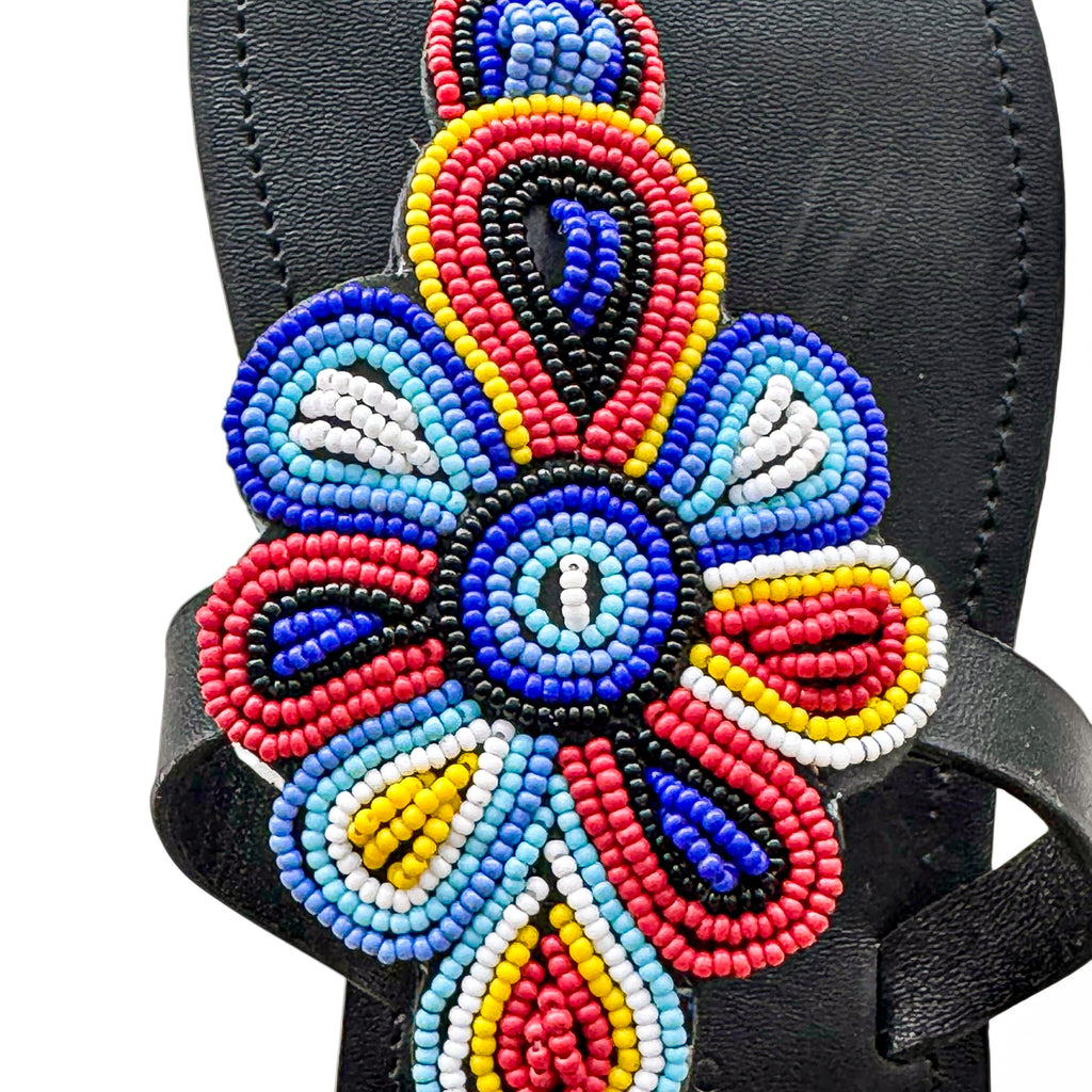 Close up of multicolor floral beadwork on Tausi black leather sandal
